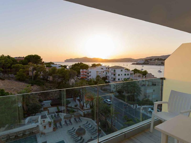 Widok z balkonu z krzesłem na zachód słońca, basen i budynki w ośrodku wypoczynkowym.