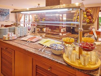 Buffet mit Glashaube, Schalen, Tellern, Gläsern und diversen Speisen auf einer Granitplatte.