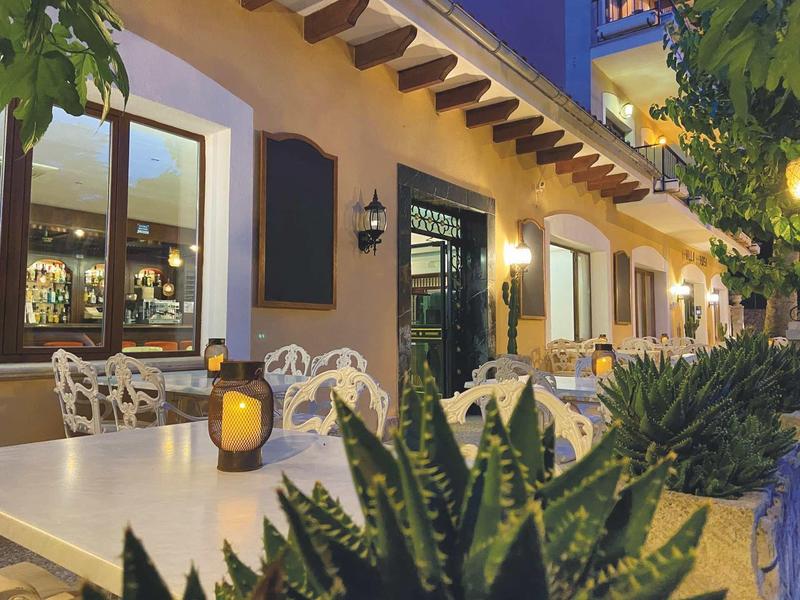 Accogliente area esterna di un hotel con tavoli, sedie e illuminazione decorativa