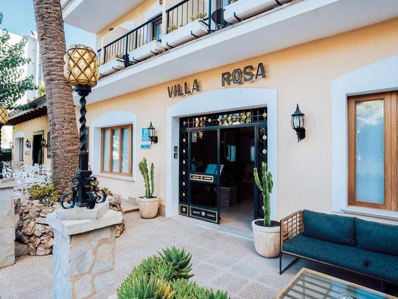 Vista esterna dell'ingresso di Villa Rosa con area salotto e decorazioni vegetali