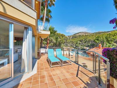 Terras met twee blauwe ligstoelen, glazen deur en uitzicht op groene heuvels onder een blauwe lucht.