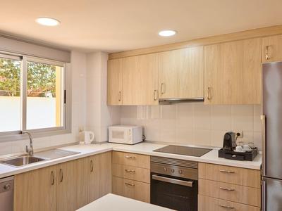 Moderne keuken met houten kasten, roestvrijstalen apparaten en groot raam met natuurlijk licht.