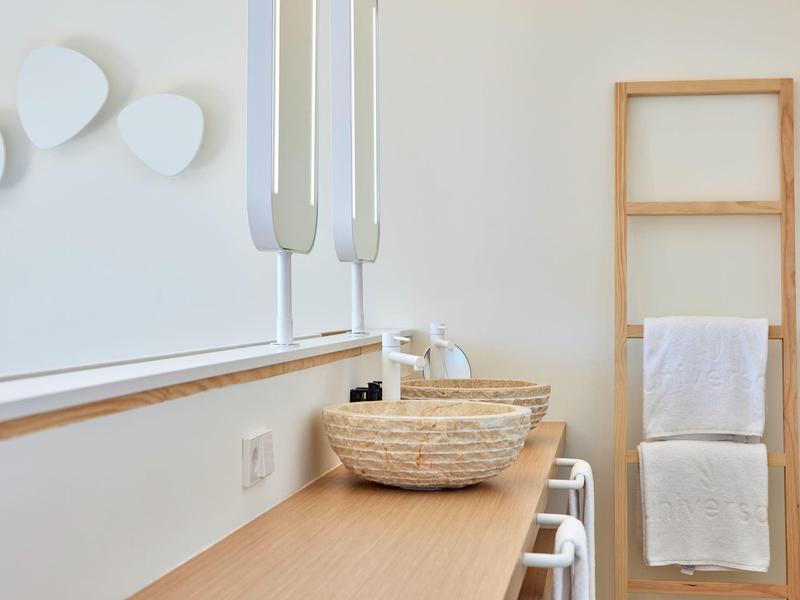 Lichte badkamer met houten accenten, witte wanddecoratie en gevlochten wasbak