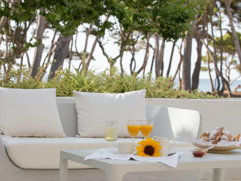 Gemütliche weiße Couch im Garten mit Getränken, Sonnenblume und Snacks auf dem Tisch.