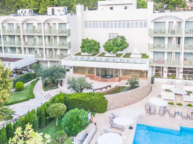 Moderner Hotelkomplex mit grünem Garten, Pools und hellen, mehrstöckigen Gebäuden.