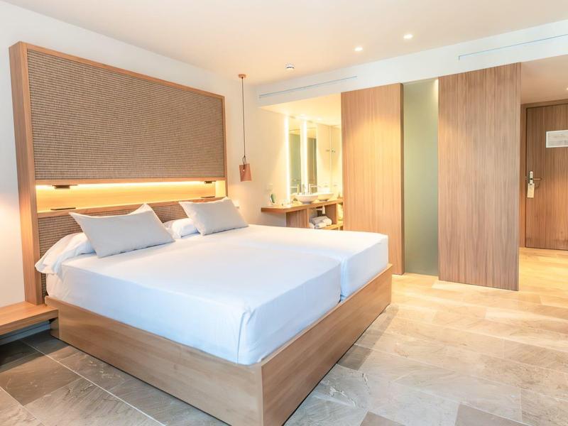 Modern eingerichtetes Schlafzimmer mit großem Bett, Holzdetails und warmem Licht.