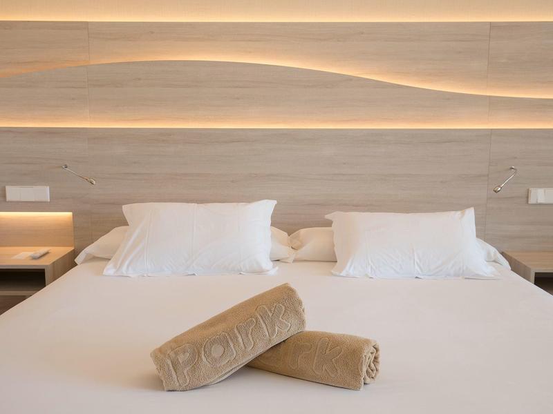 Ein großes Bett mit weißer Bettwäsche, zwei Kissen und zwei braunen Handtüchern davor.