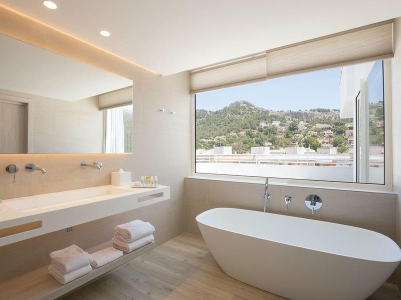 Helles Badezimmer mit freistehender Badewanne, großer Fensterfront und modernem Waschbecken.