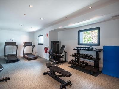 Una palestra luminosa con tapis roulant, pesi e panca per allenamento in un hotel.