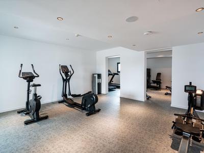 Palestra moderna in hotel con macchine cardio e di forza su pavimento grigio chiaro.