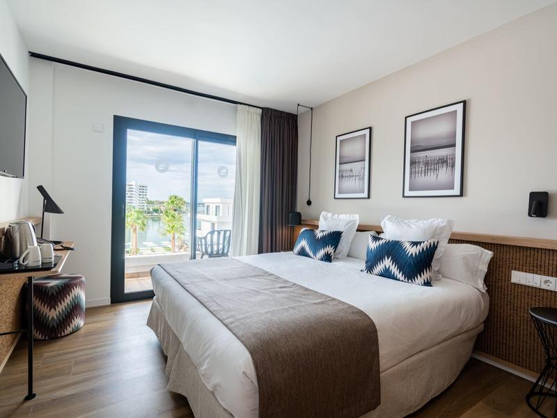 Moderní hotelový pokoj s velkou postelí, balkonem a elegantním zařízením.