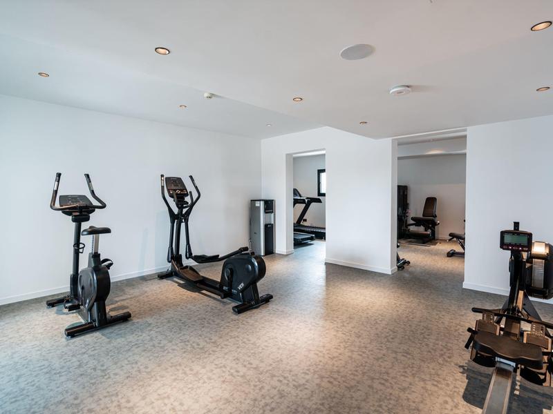 Moderní posilovna s běžeckými pásy a cvičebními stroji v hotelu.