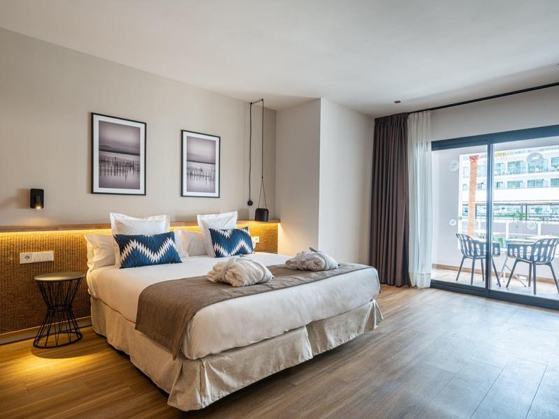 Moderní hotelový pokoj se dvoulůžkem, balkonem a přirozeným světlem.