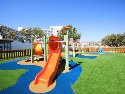 Colorida zona de juegos infantiles con tobogán sobre césped verde bajo un cielo azul claro