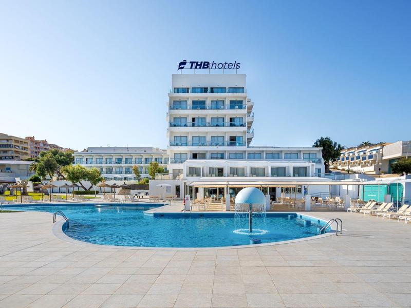 Hôtel moderne avec une grande piscine ronde et des chaises longues sous un ciel clair.