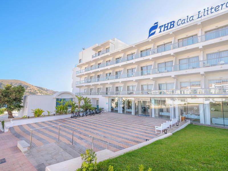 Hôtel moderne à plusieurs étages avec balcon, terrasse spacieuse et pelouse verte bien entretenue.
