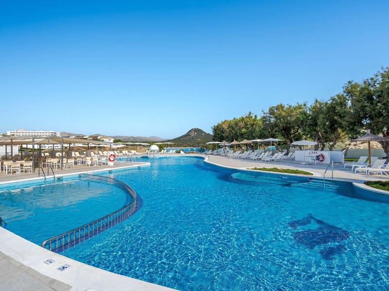 Piscine extérieure avec chaises longues et paysage urbain en arrière-plan.