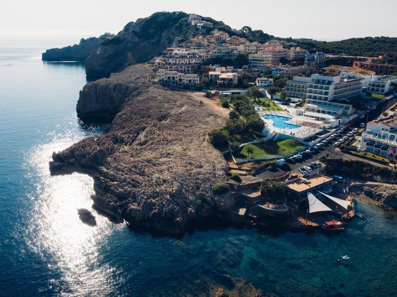 Complexe hôtelier en bord de mer avec piscine et zones rocheuses en Méditerranée.