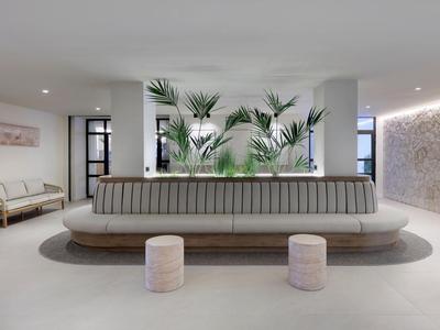 Jasna lobby hotelowa z nowoczesnym okrągłym miejscem do siedzenia i zielonymi roślinami jako punktem centralnym.