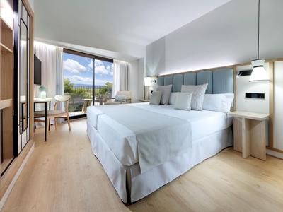 Jasny pokój hotelowy z podwójnym łóżkiem, drewnianą podłogą i widokiem na taras.