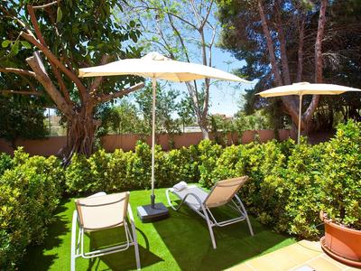 Due sdraio con ombrelloni in un giardino soleggiato circondato da vegetazione rigogliosa.