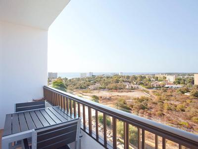 Balcone con sedie che si affaccia su un paesaggio secco e edifici distanti sotto un cielo limpido.