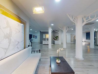 Hall dell'hotel moderno con sedute bianche, colonne a forma di albero e tavolo in legno scuro.