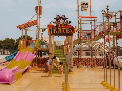 Parque acuático colorido con toboganes y temática de barco pirata en un resort vacacional.