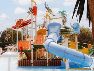 Parque acuático colorido con toboganes y juegos de agua en una piscina al aire libre.