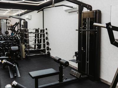 Equipos de fitness modernos en un gimnasio de hotel compacto con alfombrillas negras y espejos.