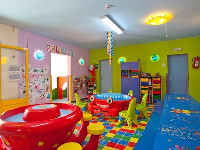 Sala giochi colorata per bambini con giocattoli, tappeti e pareti luminose in hotel o vacanza.