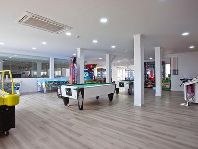 Duża strefa gier z stołem do bilardu, hokejem powietrznym i automatami do gier w jasnym pokoju z drewnianą podłogą.