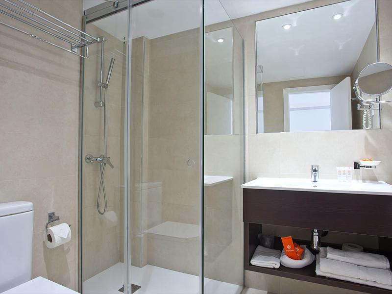 Bagno moderno con doccia in vetro, WC bianco, mobile scuro e grande specchio.