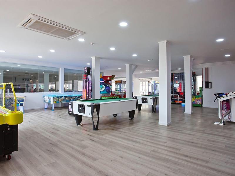 Ampia sala giochi dell'hotel con tavolo da biliardo, macchine arcade e hockey da tavolo.