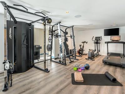 Moderner Fitnessraum mit Trainingsgeräten und Zubehör in einem Hotelzimmer.