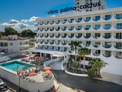 Modernes Hotel mit weißer Fassade, Balkonen und beheiztem Pool unter blauem Himmel.