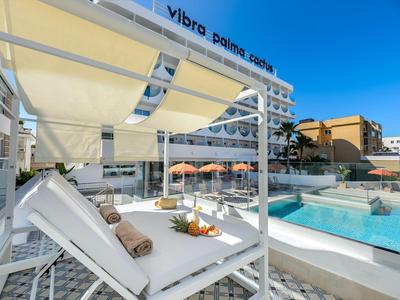 Moderner Hotelpool mit Liegestühlen, Sonnenschirmen und klar blauem Wasser an einem sonnigen Tag.