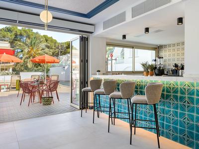 Moderne Hotelbar mit türkisfarbenem Tresen und angrenzender Terrasse mit Orangenschirmen.
