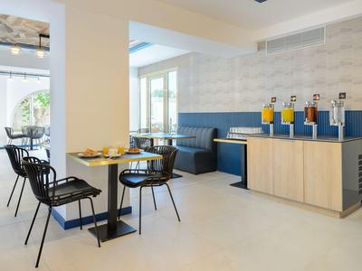 Moderner Frühstücksraum mit blauen Sitzbänken und Saftspendern in einem Hotel.