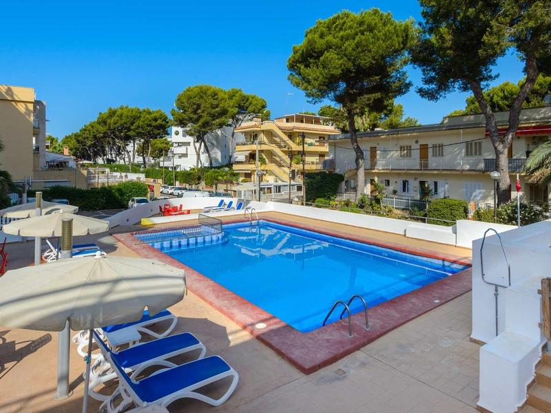 Hotelzwembad met blauwe ligstoelen en parasols onder een heldere blauwe lucht