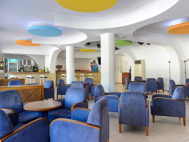 Moderne hotel lounge met blauwe fauteuils en kleine tafels onder een futuristisch plafond.