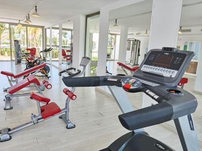 Helle und moderne Fitnessraum mit verschiedenen Trainingsgeräten und großen Fenstern