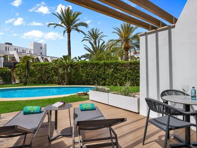 Terrazza d'hotel con piscina, lettini prendisole e tavolo rotondo sotto pergola.