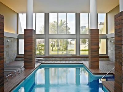 Piscina interna moderna con grandi finestre e abbondante luce naturale.