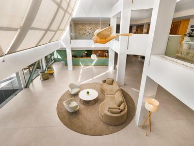 Salotto d'hotel moderno con mobili beige e grandi finestre luminose.