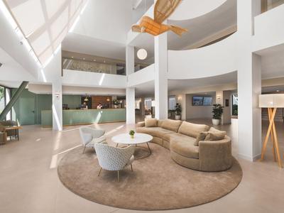 Heller, moderner Hotellobby-Bereich mit gemütlichen Sitzgelegenheiten und rundem Teppich.