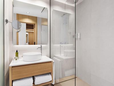 Bagno moderno con lavabo, specchio illuminato e cabina doccia in vetro.