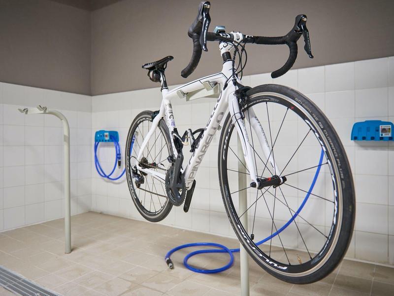 Bicicletta bianca sospesa in una stazione di pulizia o riparazione interna.