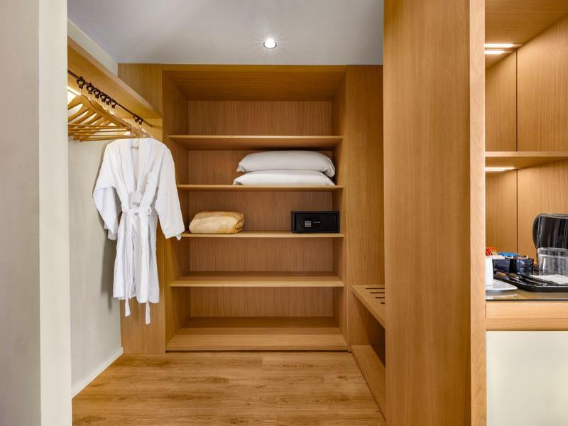 Interno di guardaroba d'hotel in legno con accappatoi, cuscini e cassaforte.