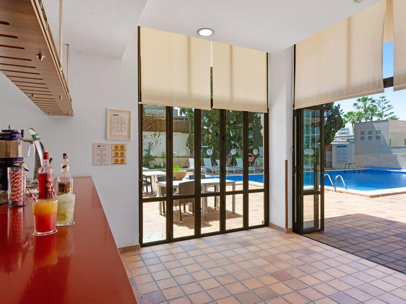 Výhled z kavárny na bazén s terasou a slunečníky.